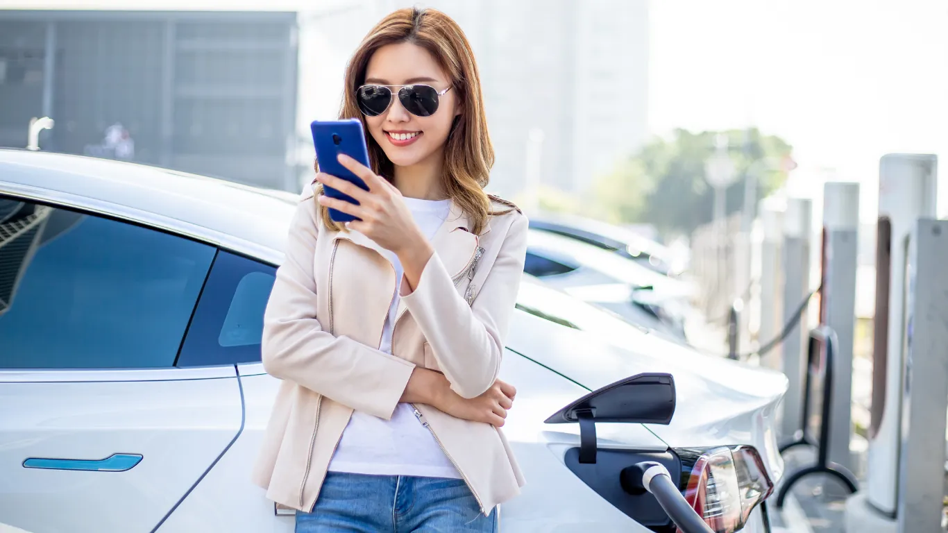 woman with a mobile in her hands. loading eletric car