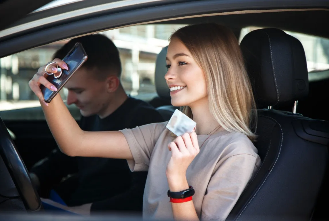 happy young woman taking selfie after getting her licence