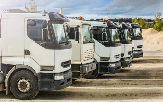 Row of white commercial trucks lined up in a yard