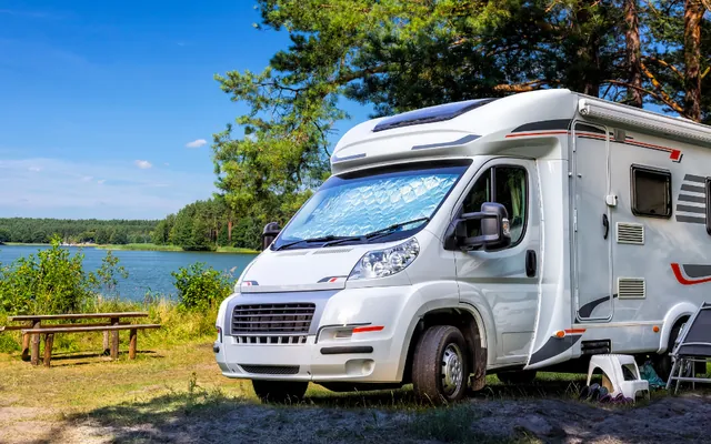 Motorhome pitched beside a lake on a sunny camping trip