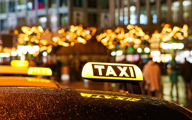 Illuminated taxi roof sign on a busy city street at night